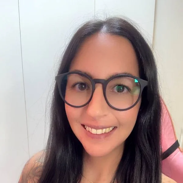 Maria Eduarda Moraes, professora de inglês, sorrindo, de óculos.